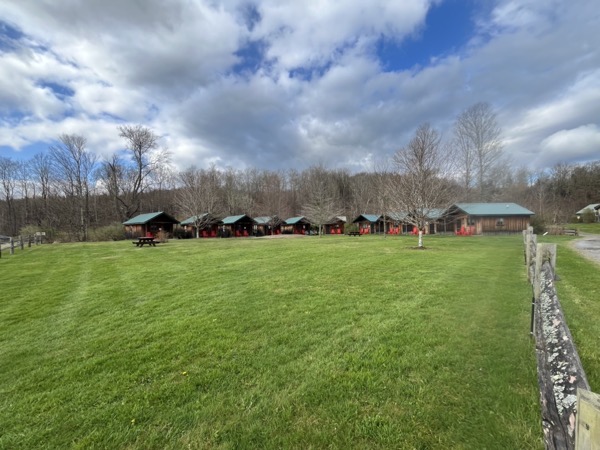 Green field. Ten tiny wood cabins line the far edge.