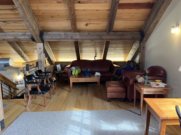 Cozy wooden loft area with comfortable stuffed chairs and tables.